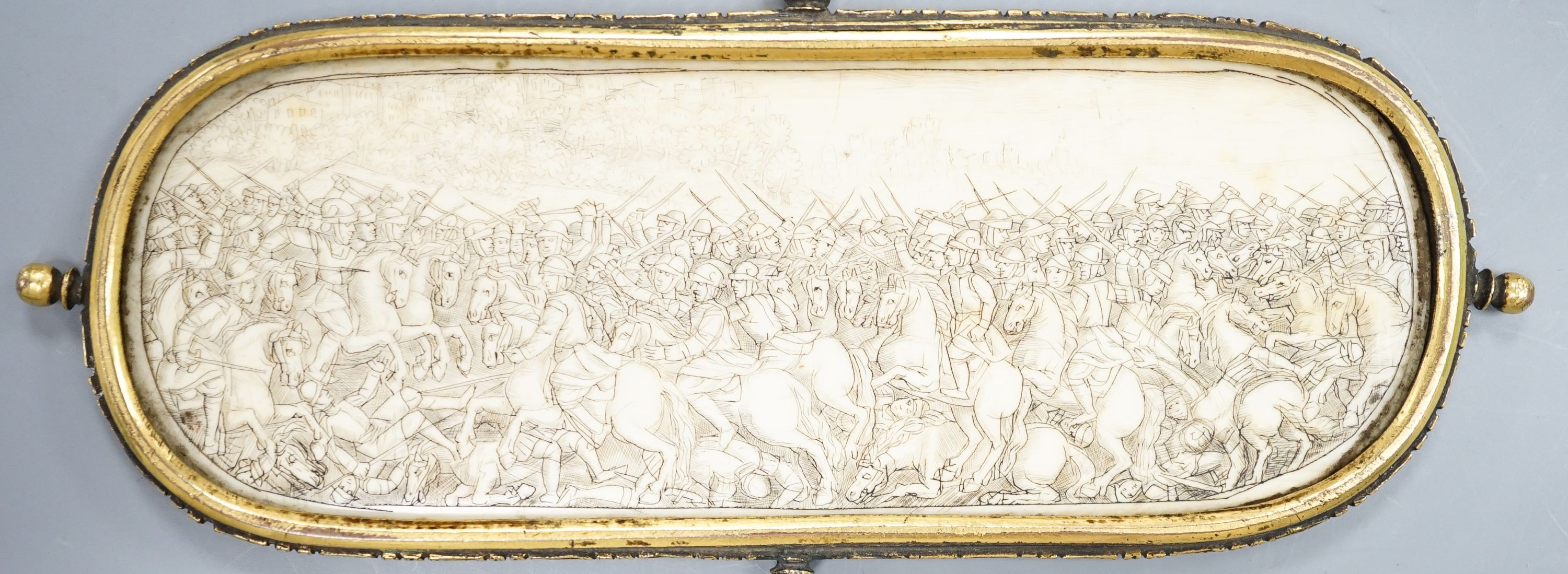 A 17th century French oval ivory plaque in a revolving metal surround, etched on both sides with battle scenes and ships in the background 17cm